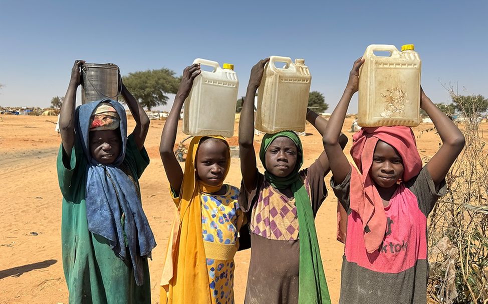 Çocuklar, Çad'daki Adré mülteci yerleşimindeki bir UNICEF sondaj kuyusunda su kaplarını doldurduktan sonra taşıyorlar. (Fotoğraf: Donaig Le Du/UNICEF)